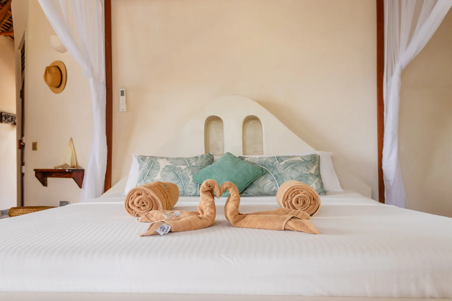King bed styled with folded towels, framed by tall windows